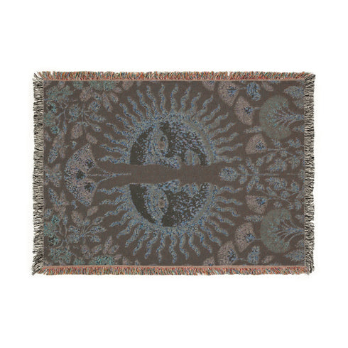 Jacquard-woven cotton blanket featuring twin celestial suns—two serene faces meeting at center—with radiant golden rays on a charcoal ground, bordered by folkloric botanicals and fan blossoms in sage, sky, and garnet. Crafted from 100% soft cotton yarn; the artwork is woven, not printed. Reversible with a color-negative back and finished with a protective 2-inch multicolor fringe. Sizes: 52×37, 50×60, 60×80 for wall, sofa, or queen-bed layering.